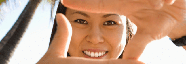 A woman is smiling through her fingers