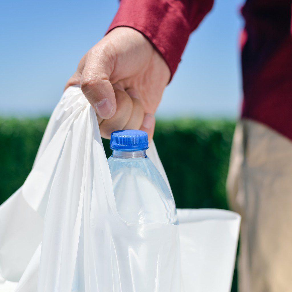 A person holding onto plastic bags and water bottle