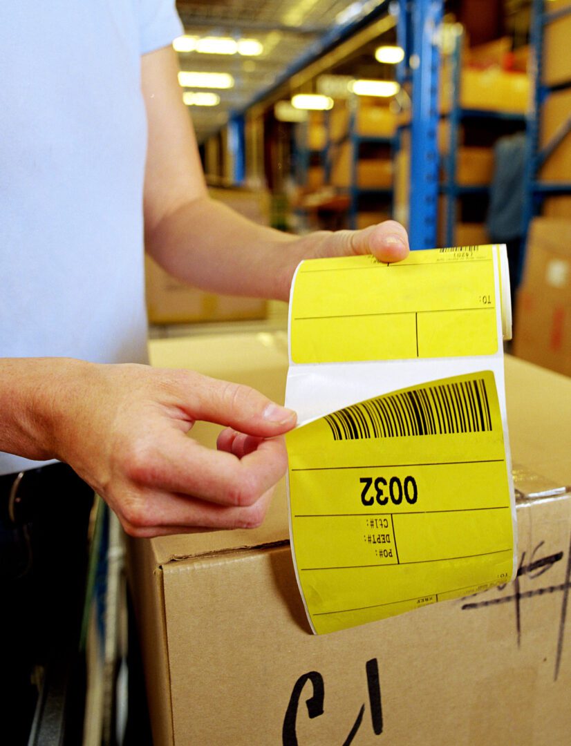 A person holding a yellow label in front of boxes.